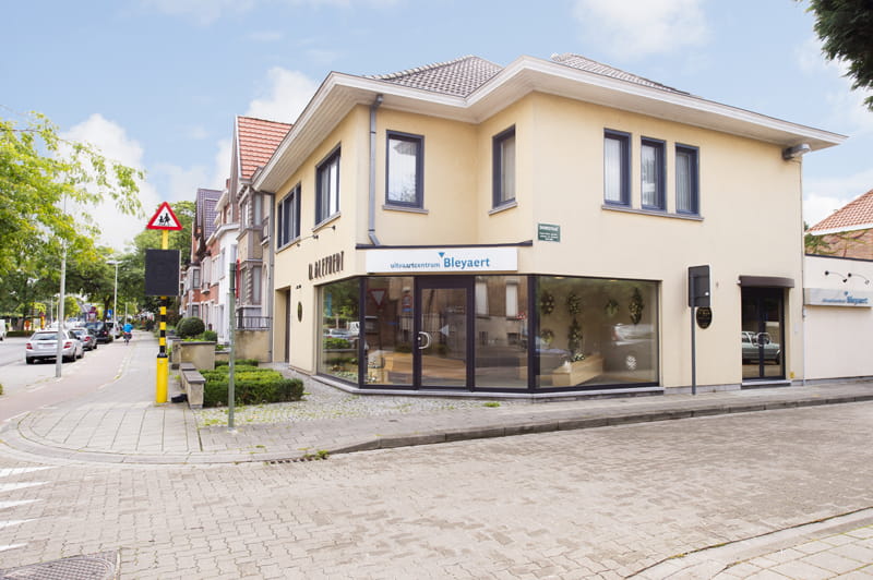 Buitengevel aanzicht met beige baksteen, vitrineramen waarboven Uitvaartzorg Bleyaert DELA staat